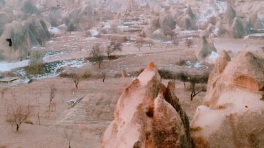 A landscape with numerous hot air balloons in a rugged terrain with unique rock formations.