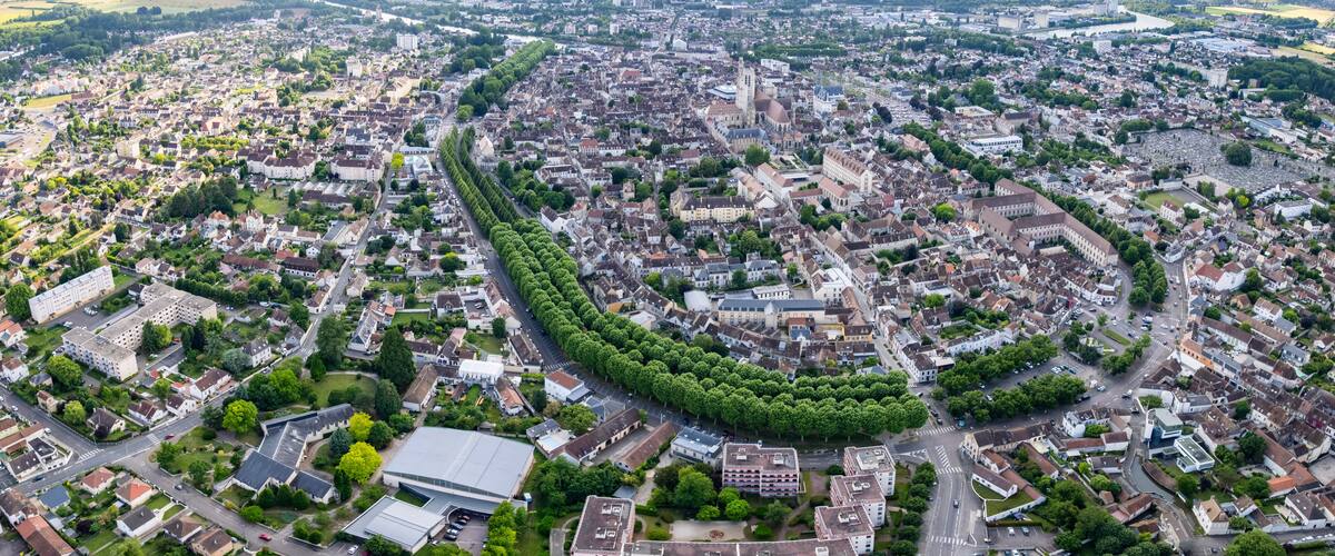 An aerial view of a city with a prominent church, a dense residential area, and a river in the background.