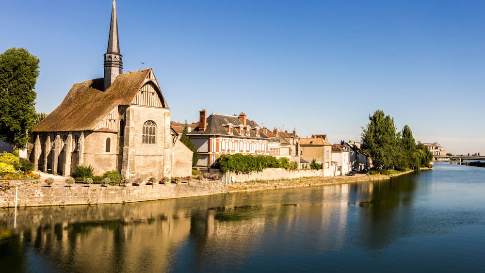 Une Ă©glise historique dotĂ©e dâun clocher imposant, une riviĂšre paisible et des bĂątiments traditionnels qui bordent ses rives.