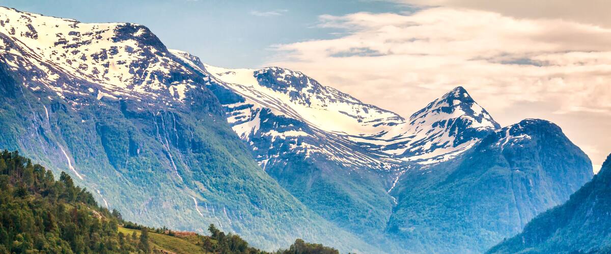 A mountainous village with snow-capped peaks, green fields, and traditional houses.