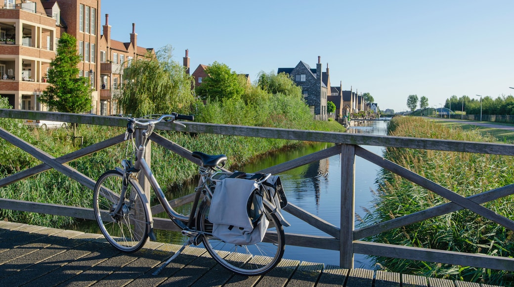 Canal view from bridge in Hoofddorp, the Netherlands. With a bicycle in the foreground. A few new-built buildings, a lot of greens.