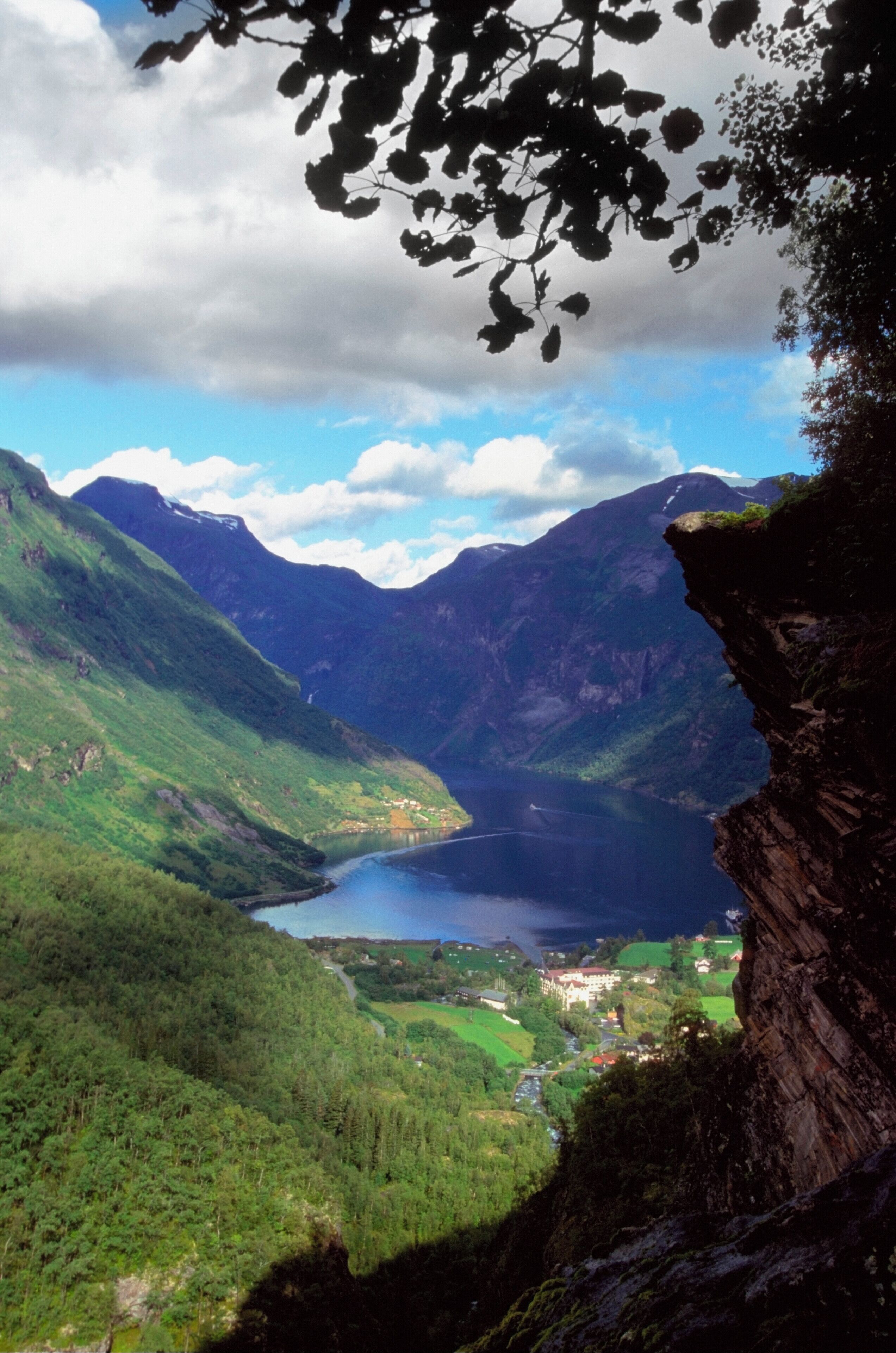 A mountainous landscape with a lake, green valleys, and a village.