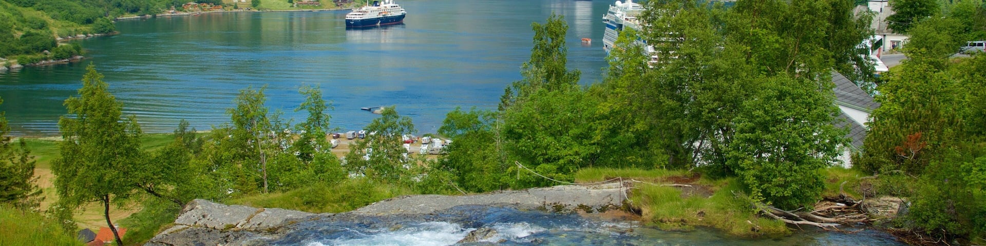 A river flowing through a mountainous landscape with a cruise ship in the background.