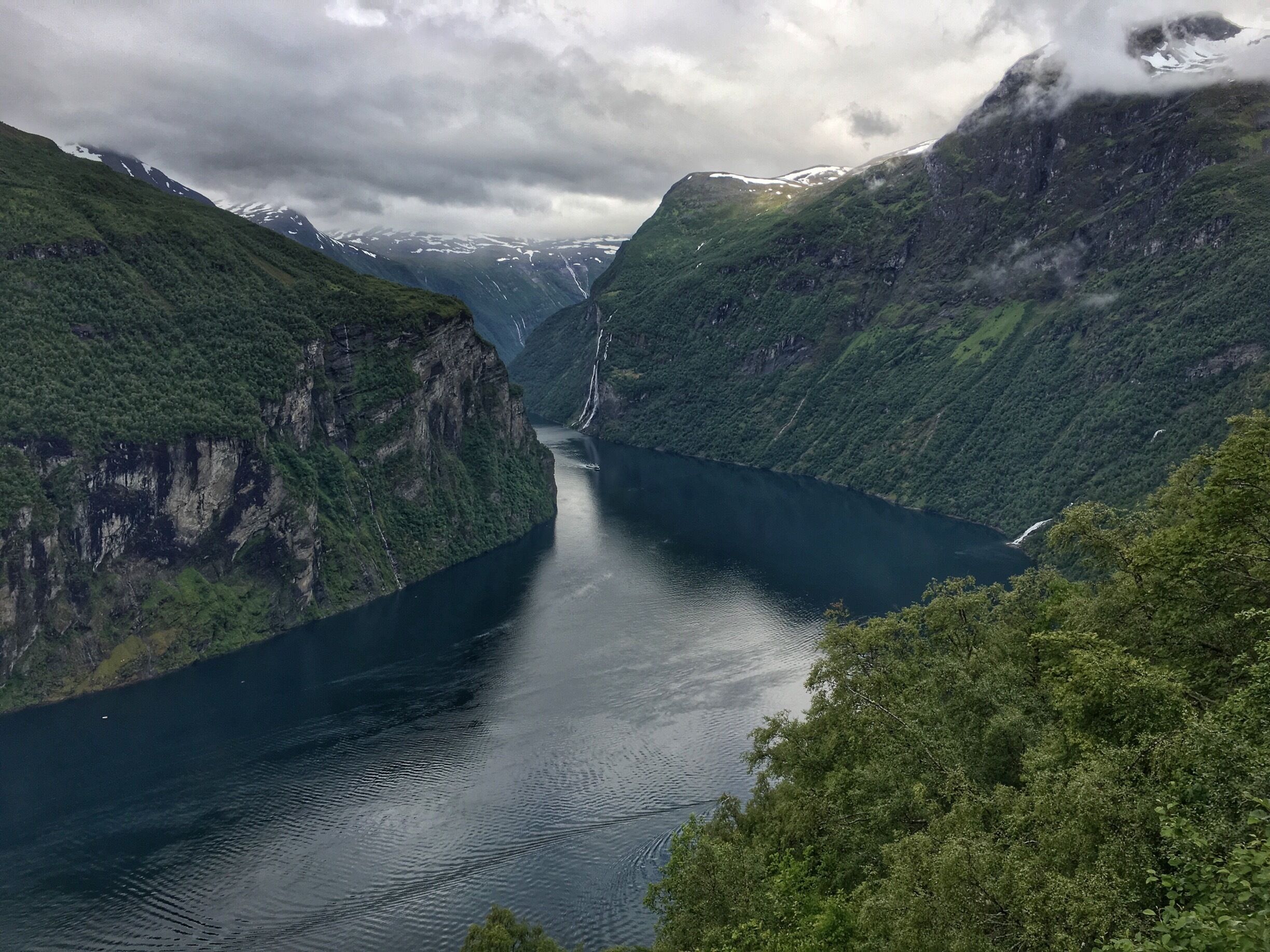 A fjord surrounded by steep, green cliffs with a river flowing through it.