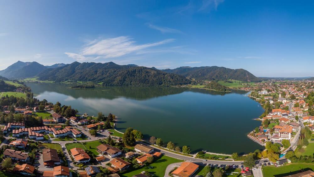 Un lac entouré de montagnes et une ville aux maisons aux toits rouges.