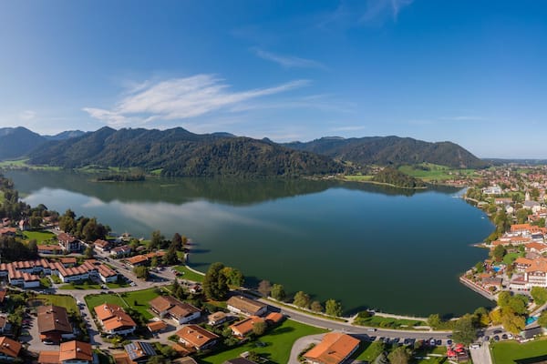 Ein See, umgeben von Bergen und einer Stadt mit roten Dächern.