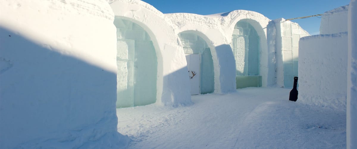 An ice hotel with snow-covered walls and arched doorways.