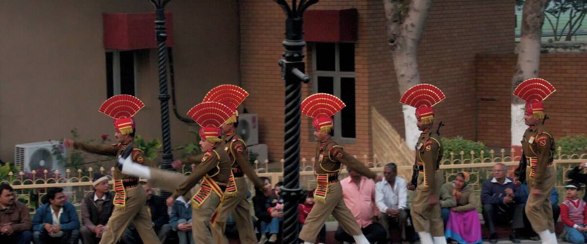A parade with performers in traditional costumes and red fans.