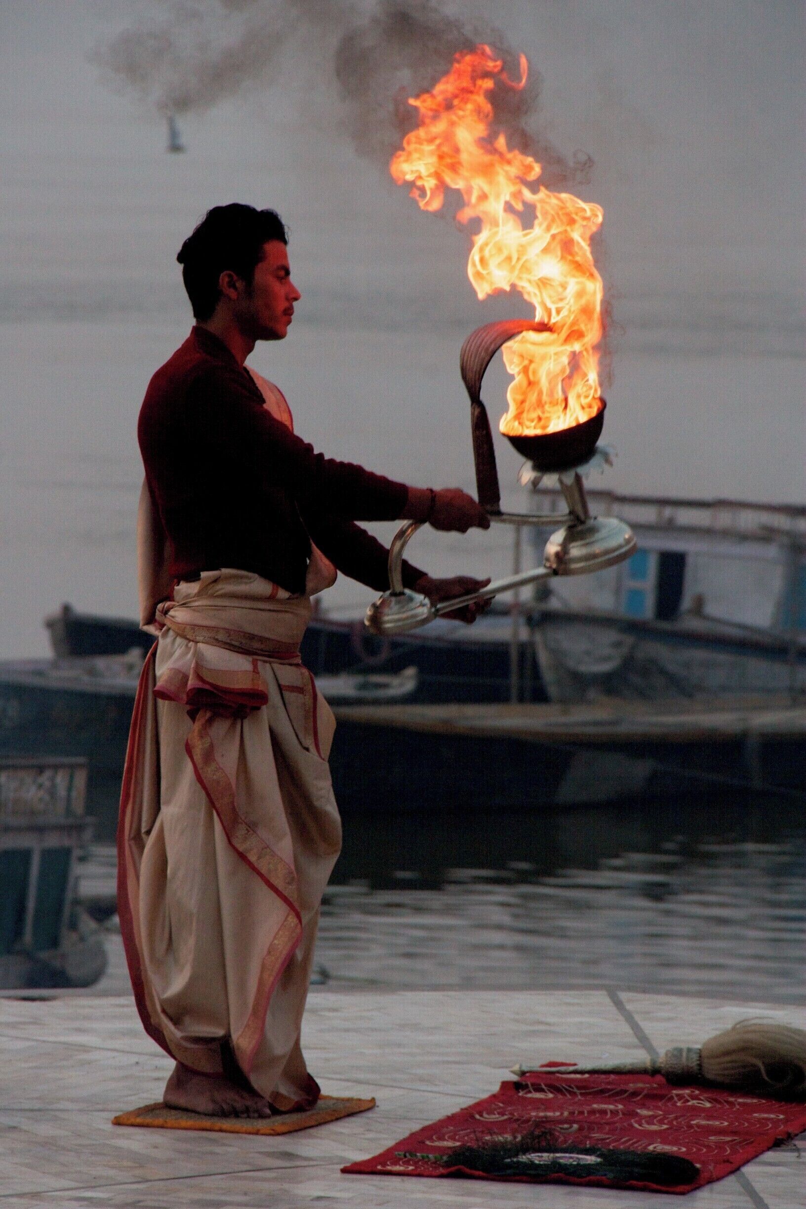 Uma pessoa realizando um ritual com fogo perto da água.