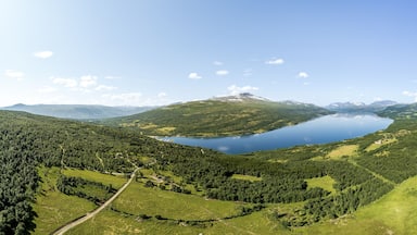 Expansive panoramic aerial view showcases Gjevilvatnet lake surrounded by the majestic Trollheimen and Innerdalen mountain range, highlighting natural beauty and serene landscapes in Oppdal, Norway