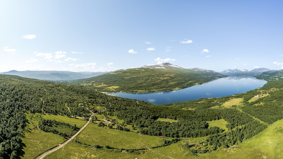 Expansive panoramic aerial view showcases Gjevilvatnet lake surrounded by the majestic Trollheimen and Innerdalen mountain range, highlighting natural beauty and serene landscapes in Oppdal, Norway