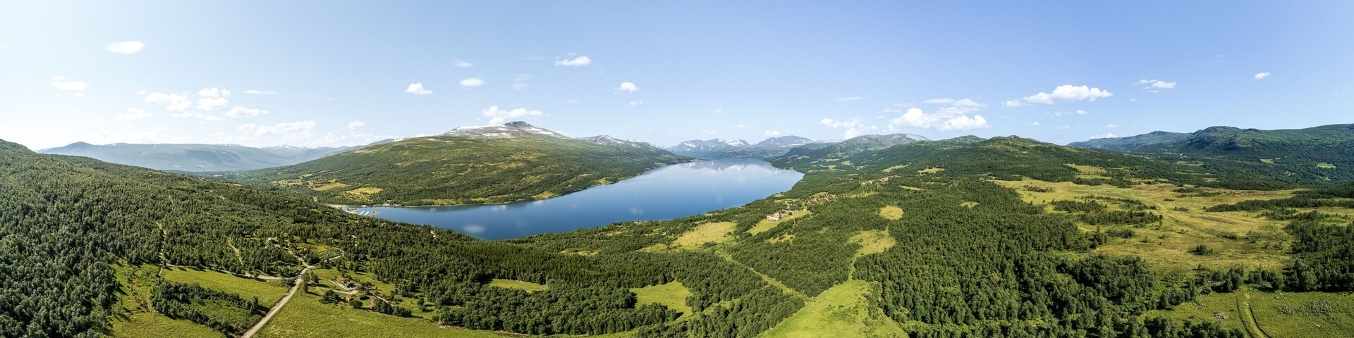 Expansive panoramic aerial view showcases Gjevilvatnet lake surrounded by the majestic Trollheimen and Innerdalen mountain range, highlighting natural beauty and serene landscapes in Oppdal, Norway
