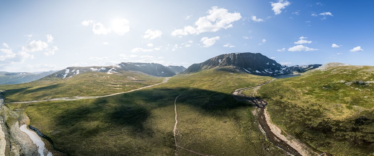 Experience breathtaking aerial panoramic view of Blåhøa mountain and Blåhøtjønna lake in the stunning Trollheimen area of Oppdal, Norway under bright sunlight and a clear blue skies in summer