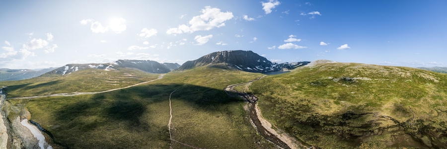 Experience breathtaking aerial panoramic view of Blåhøa mountain and Blåhøtjønna lake in the stunning Trollheimen area of Oppdal, Norway under bright sunlight and a clear blue skies in summer