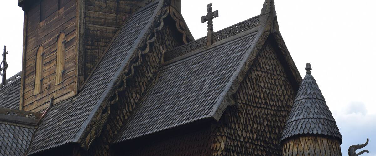 A wooden building with a steeply pitched roof and a pointed tower.