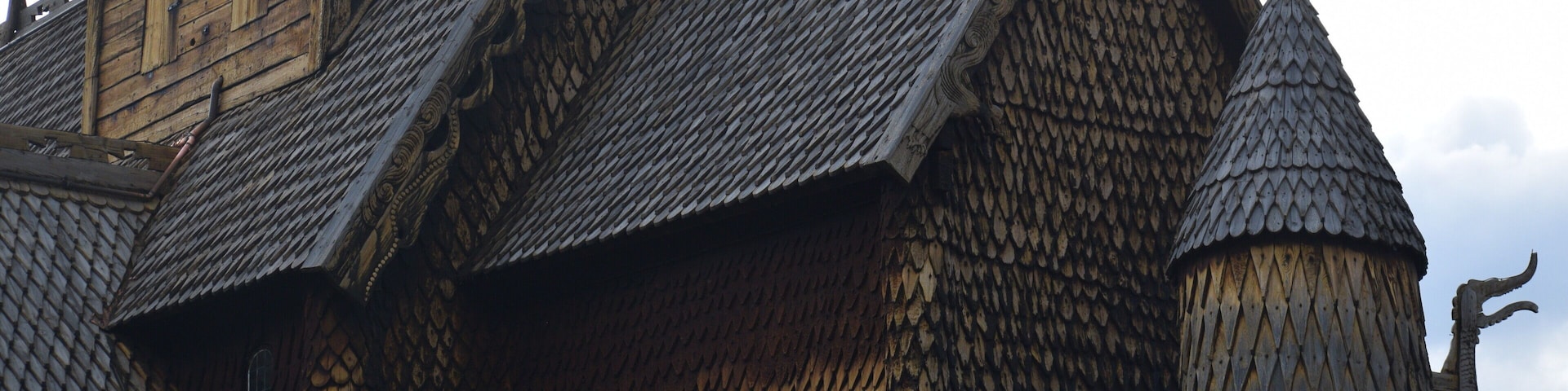 A wooden building with a steeply pitched roof and a pointed tower.