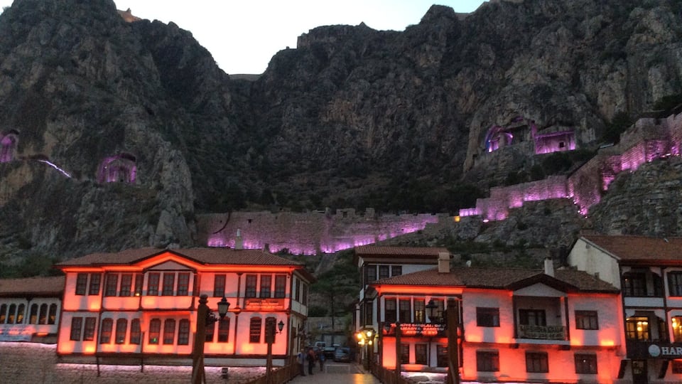A town with buildings illuminated by red lights, set against a backdrop of rocky cliffs.