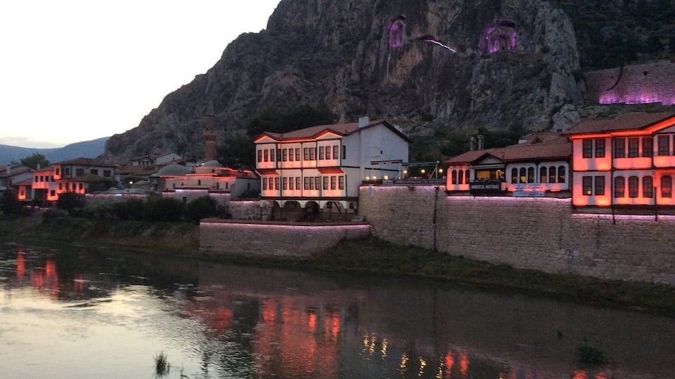 A riverside town with illuminated buildings and a mountain backdrop.