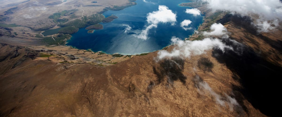 A vast landscape with a large body of water surrounded by mountains and clouds.
