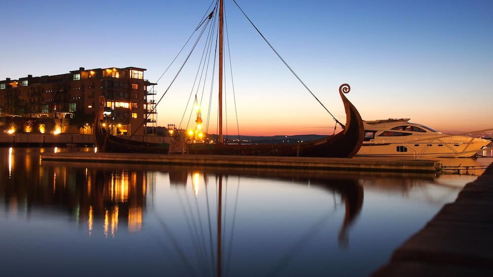 Ein traditionelles Boot liegt in einer Marina vor einer Skyline.