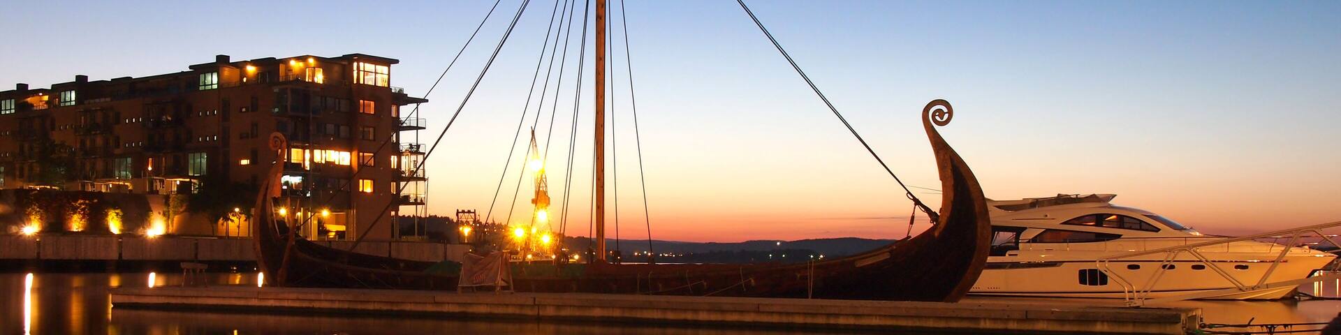 A traditional boat docked at a marina with a cityscape in the background.