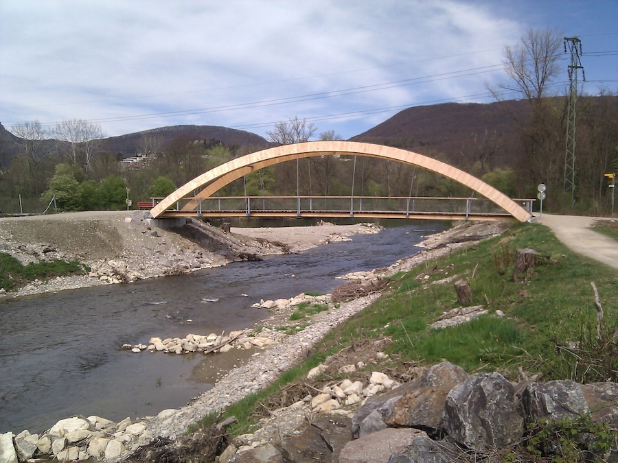 Uma ponte de pedra sobre um rio, com montanhas ao fundo.