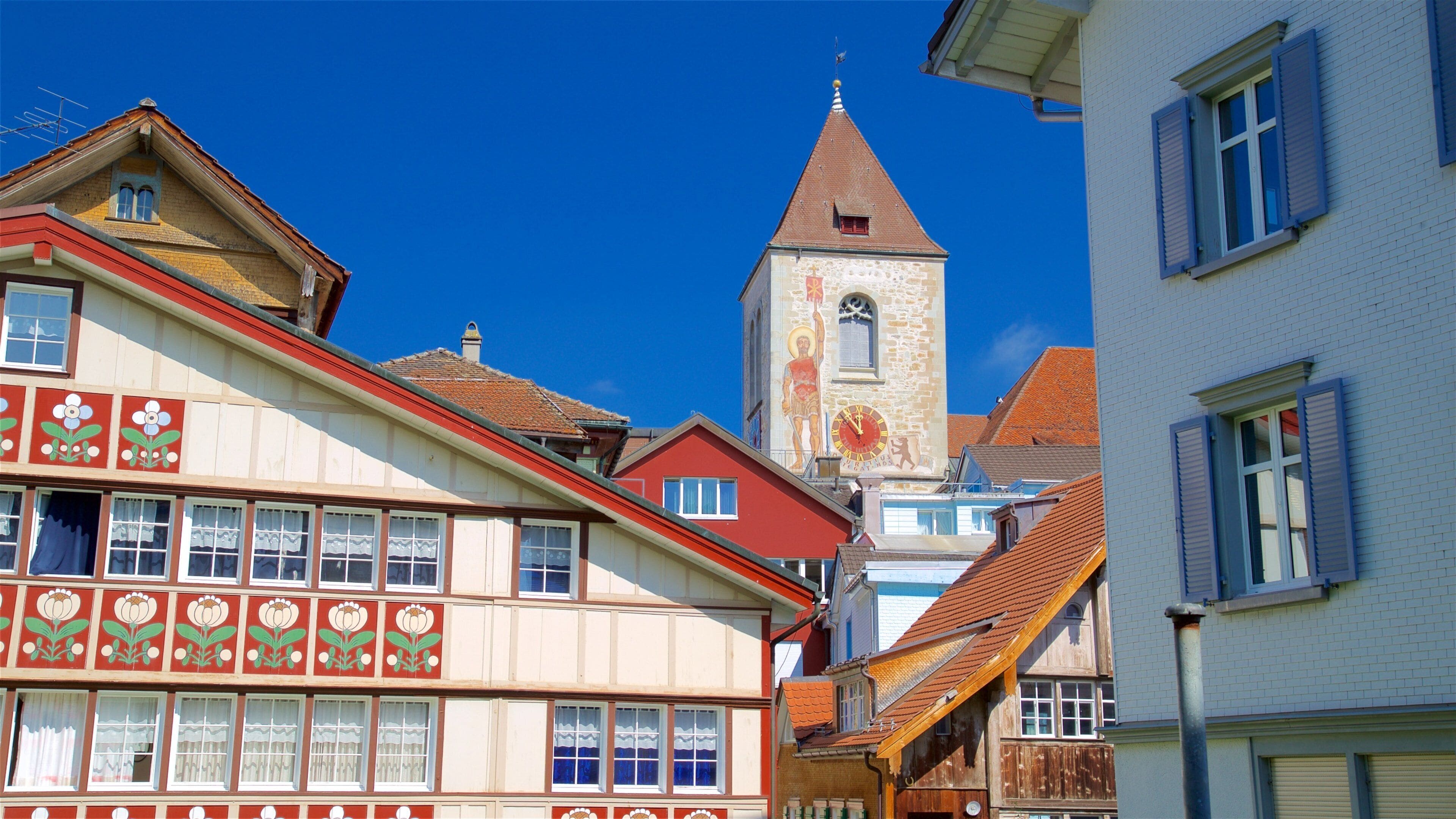 A town with colorful buildings, a church tower, and a clear blue sky.
