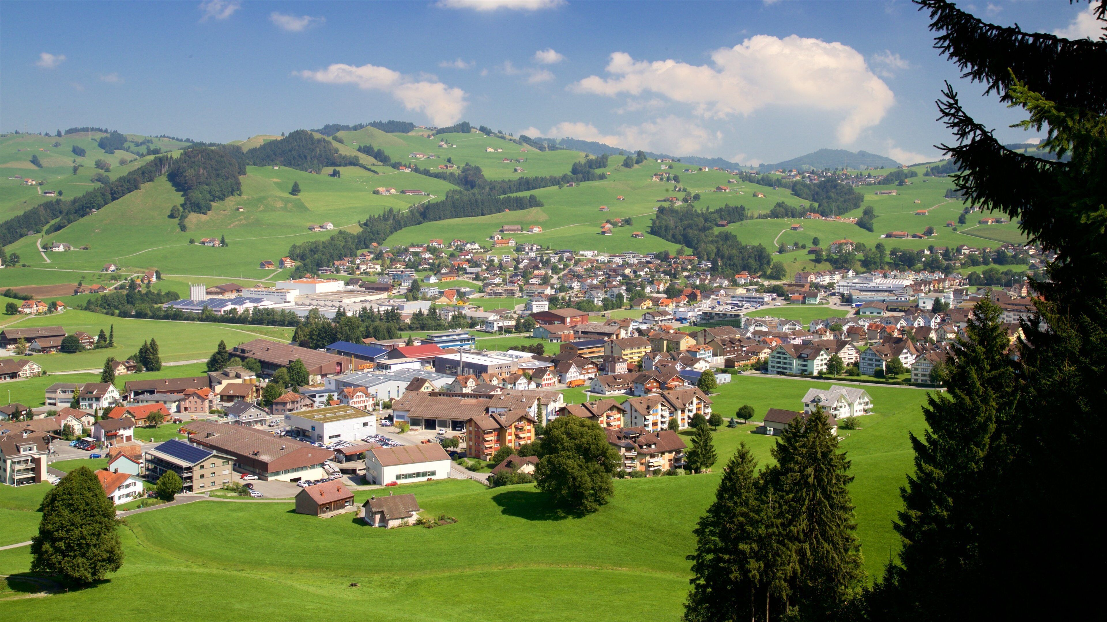 A town nestled in green hills with buildings and roads.