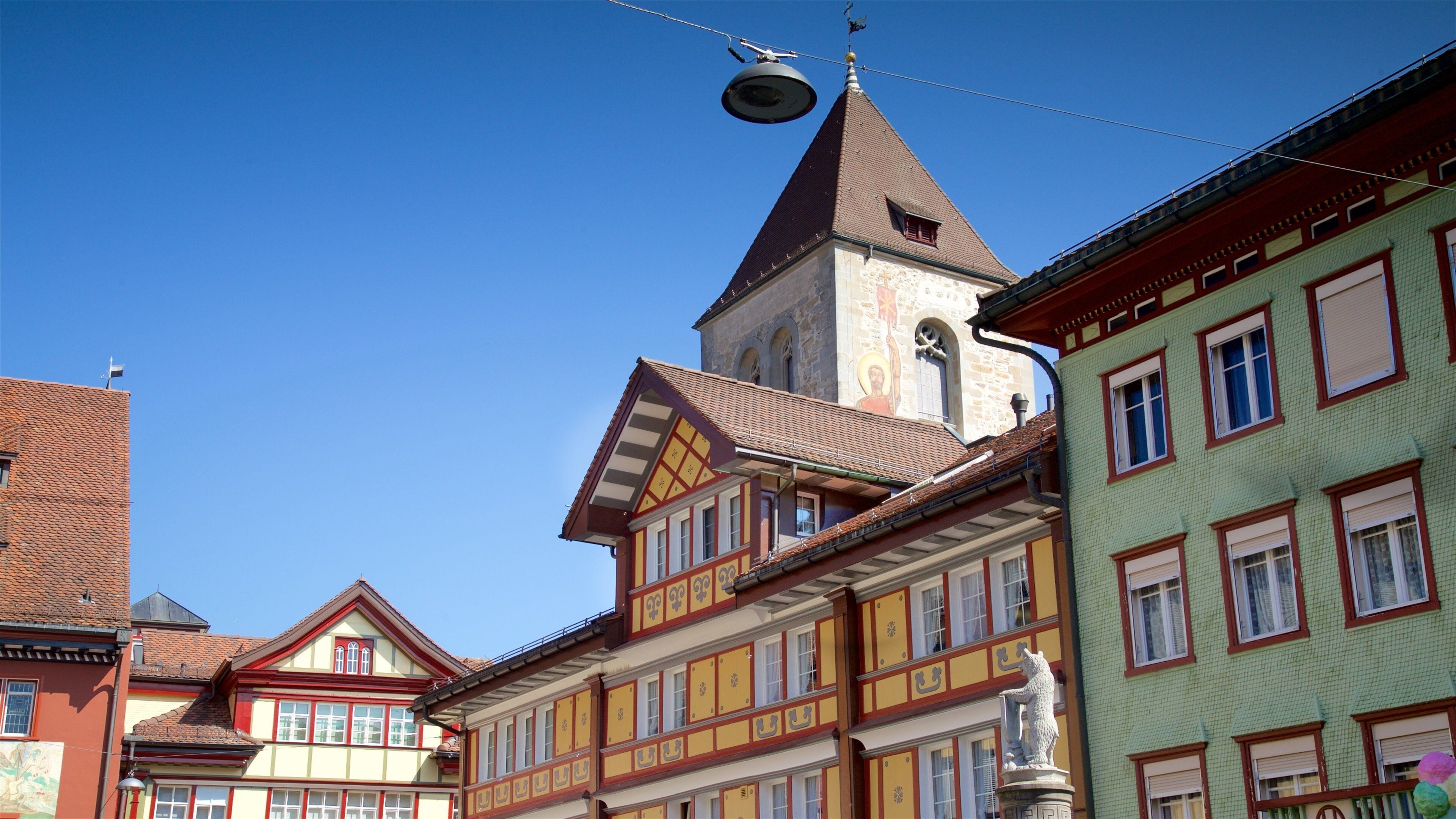 A traditional European town with colorful buildings, a church tower, and a statue.