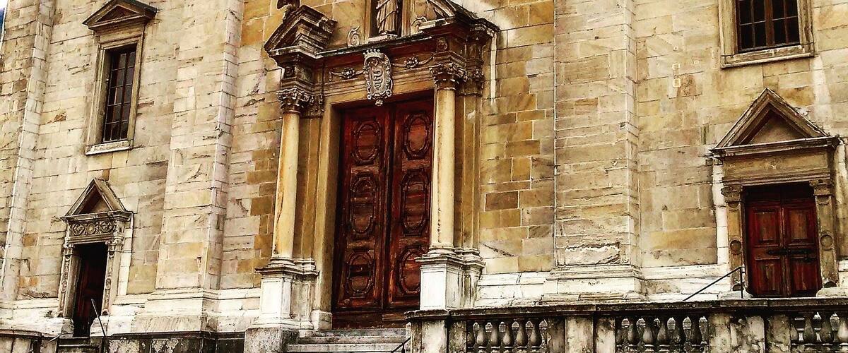 A historic building with a large wooden door, a decorative window, and a clock.