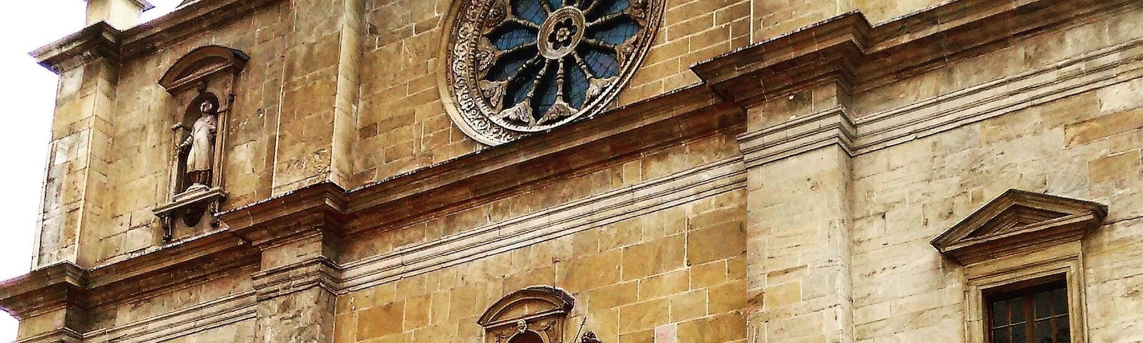 A historic building with a large wooden door, a decorative window, and a clock.