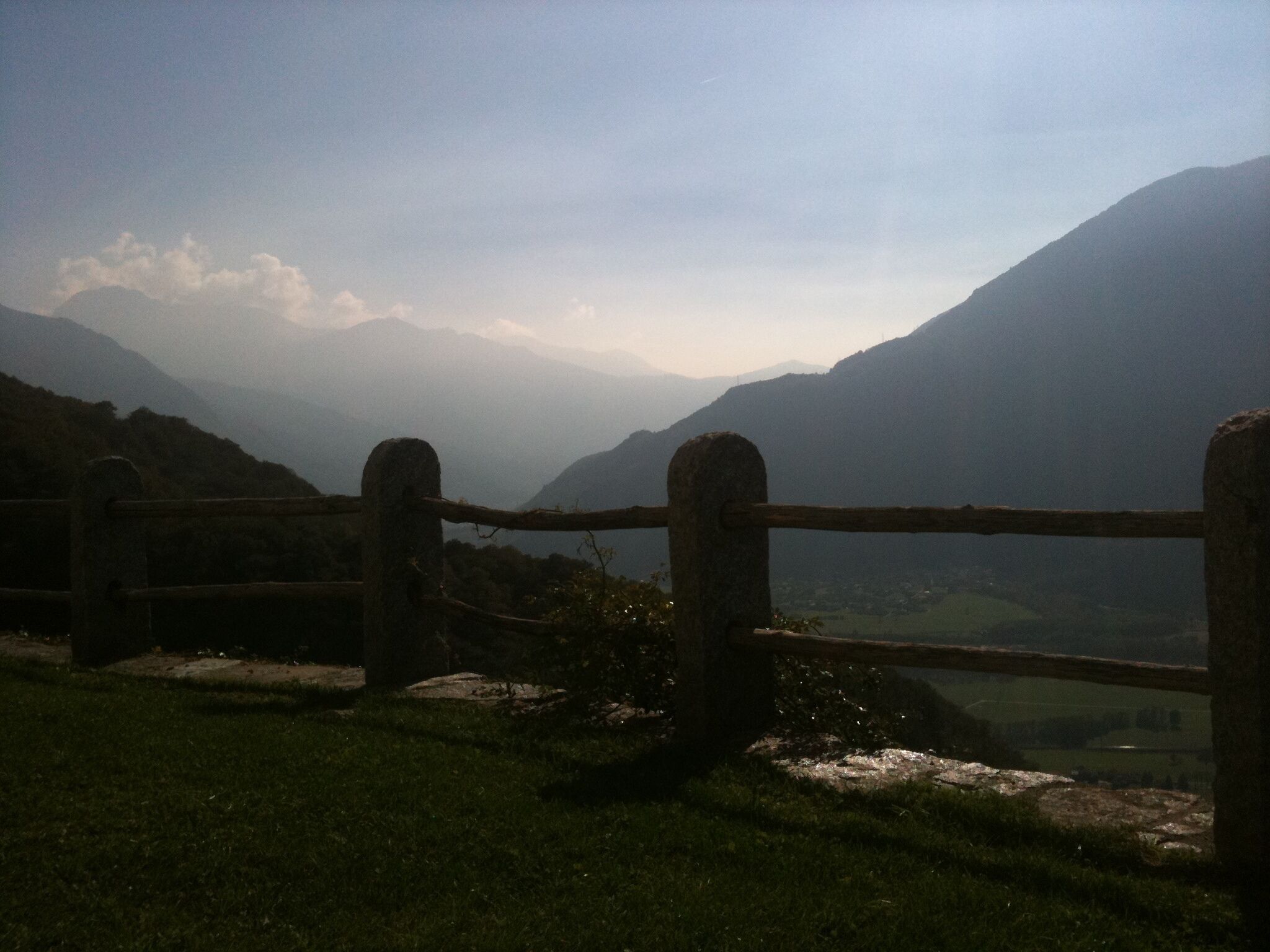 A stone fence overlooking a valley with mountains in the background.