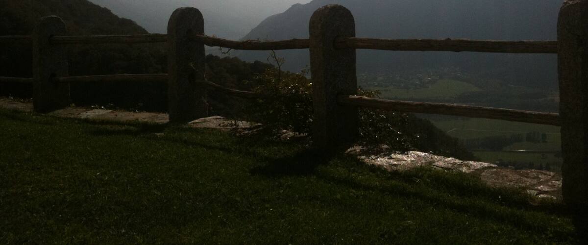 A stone fence overlooking a valley with mountains in the background.