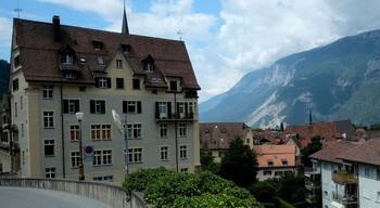 A town with historic buildings, a prominent church steeple, and mountains in the background.