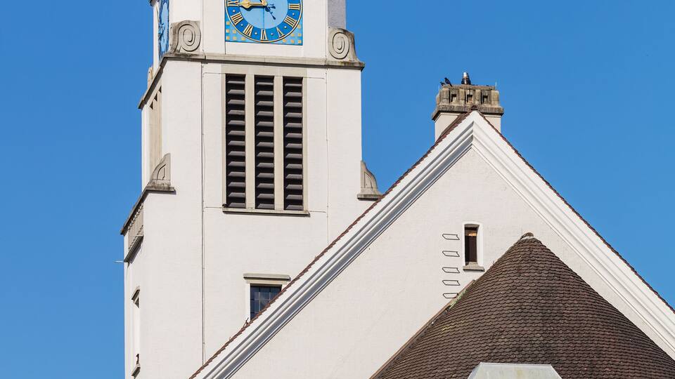 A church with a clock tower, a weather vane, and a pointed roof.