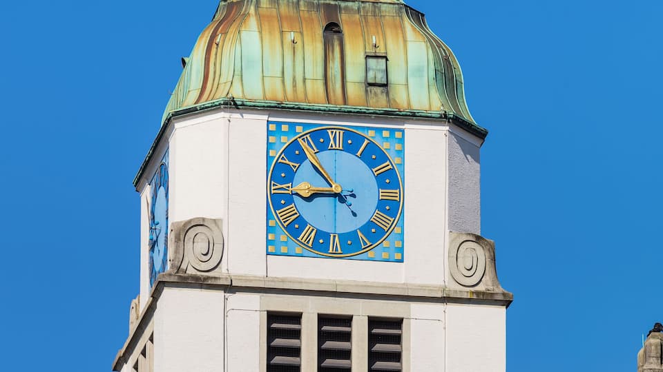 A clock tower with a blue clock face and a weather vane on top.
