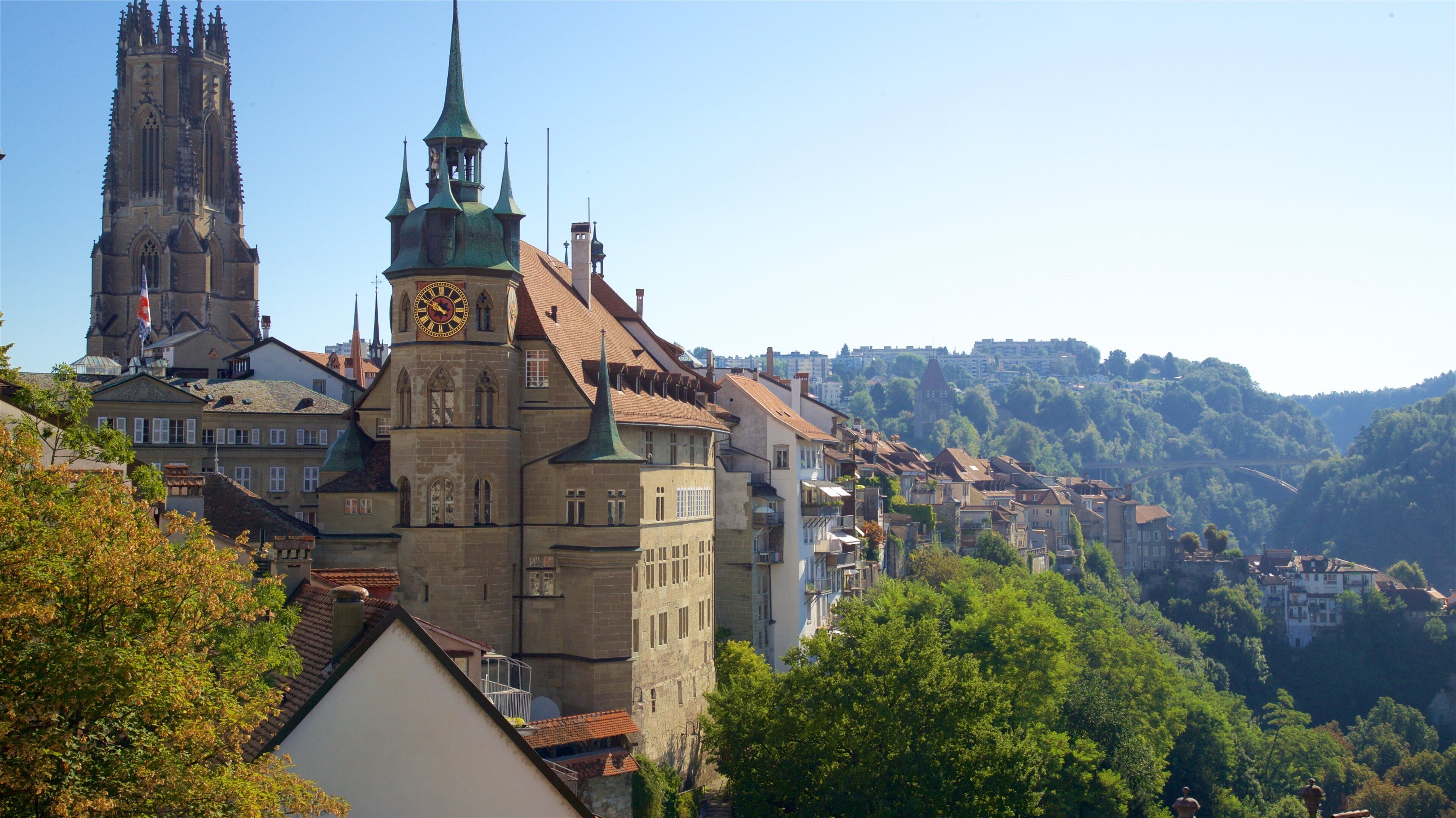 A historic town with a prominent church tower, a clock tower, and a cathedral in the background.