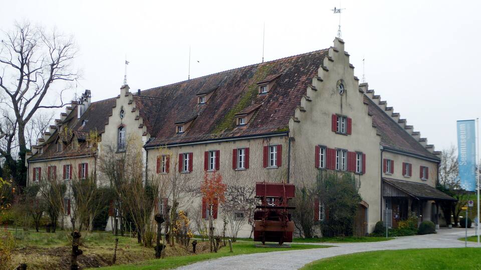 A historic building with red shutters and a weather vane.