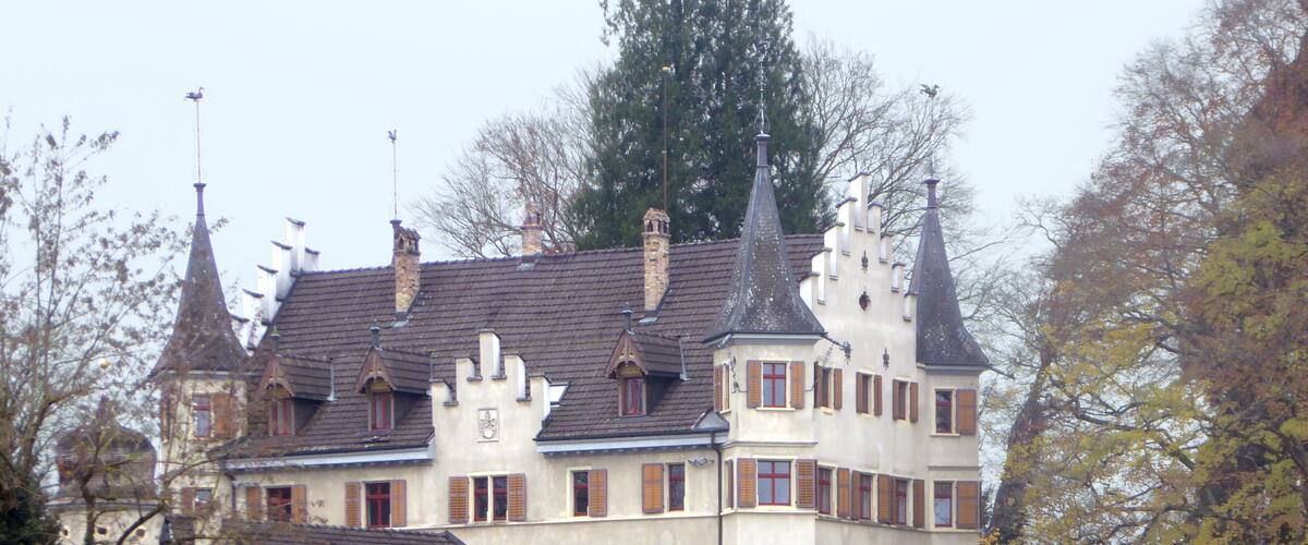 A large, historic building with multiple towers and a well-maintained garden.