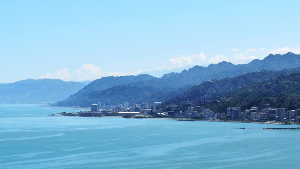 A coastal city with a mountain range in the background.