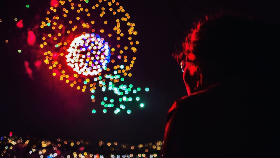 A person silhouetted against a colorful light display.