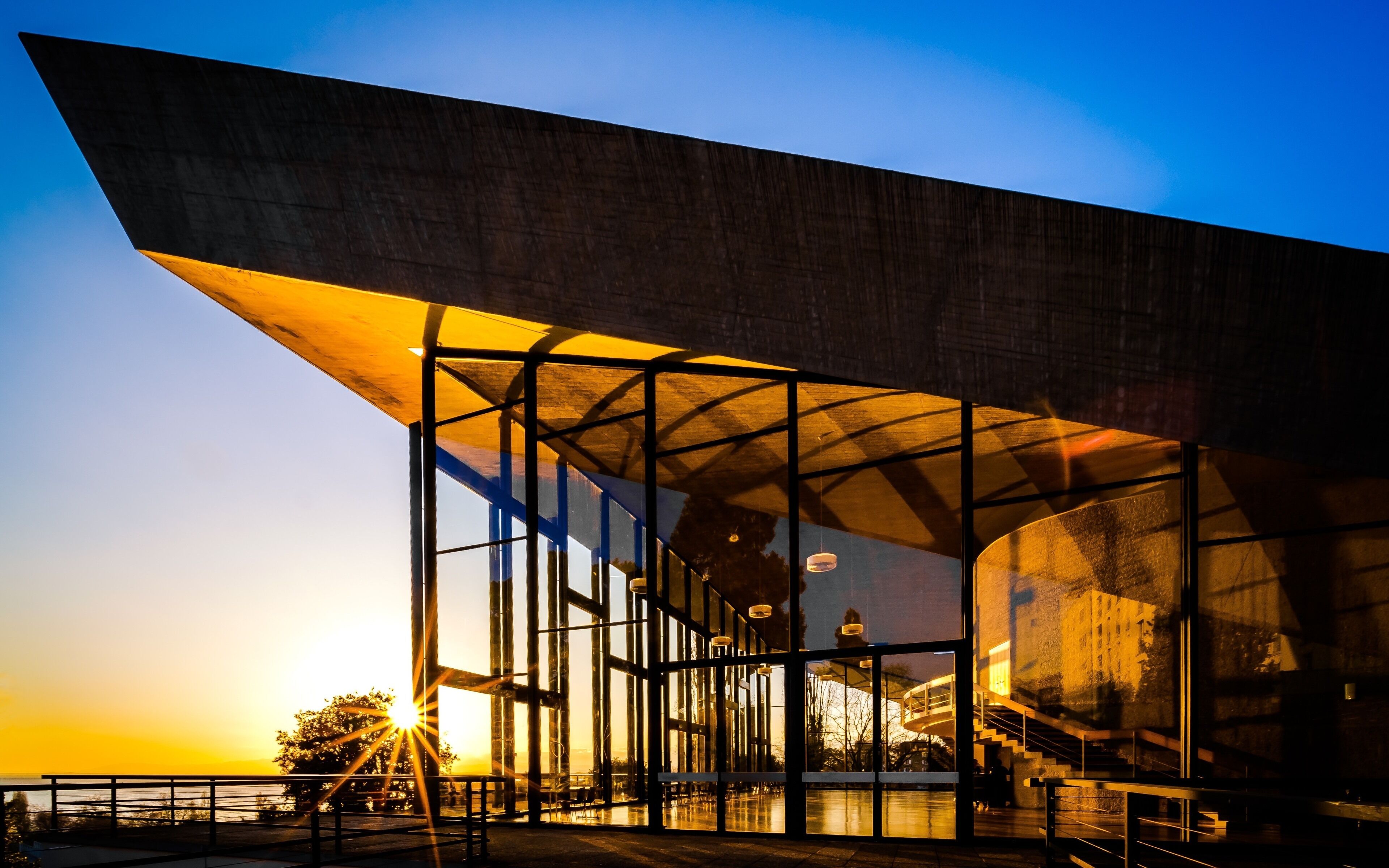 Aula des Cèdres, Jean Tschumi, 1961-1962. The rectangular building has a huge concrete roof that raises at both ends like a veil in order to allow these high windows offering a beautiful view on the trees and the lake. Perfect both for architecture enthusiasts and sunset lovers !