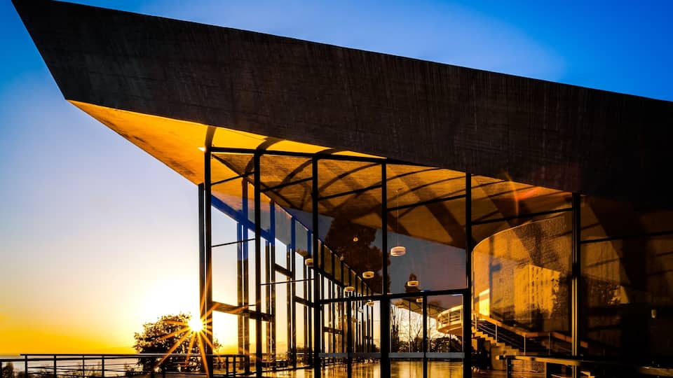 Aula des Cèdres, Jean Tschumi, 1961-1962. The rectangular building has a huge concrete roof that raises at both ends like a veil in order to allow these high windows offering a beautiful view on the trees and the lake. Perfect both for architecture enthusiasts and sunset lovers !