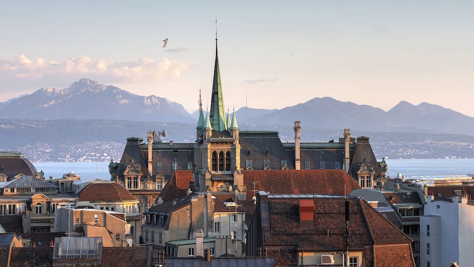 Skyline of Lausanne, Switzerland as seen from the Cathedral hill at sunset zoomed-in on the tower of St-Francois Church. Lake Leman (Lake Geneva) and the French Alps provide a beautiful background.