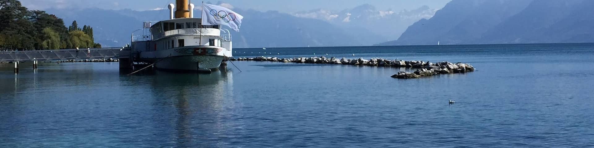 A boat docked at a pier with mountains in the background.