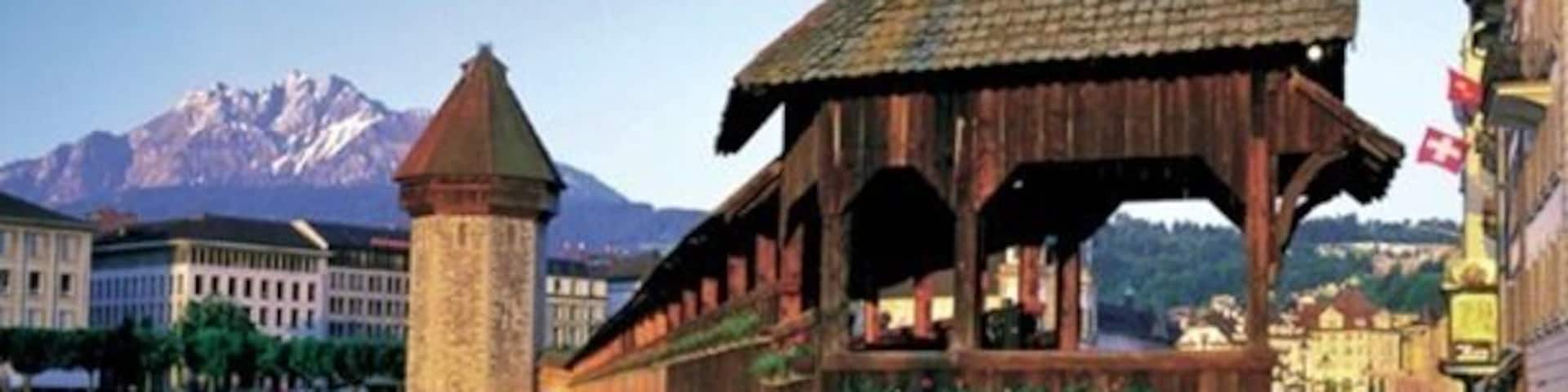A wooden pavilion over a canal with a mountain in the background.