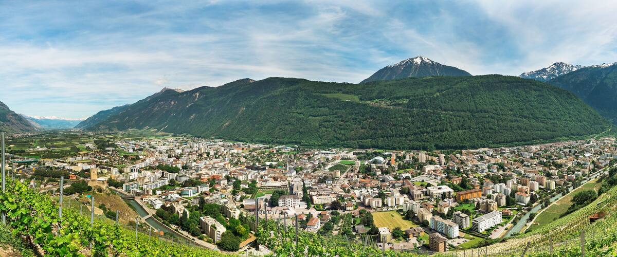 A city nestled in a valley with mountains in the background.