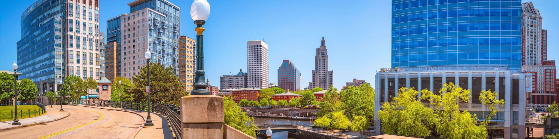 Providence City skyline, skyscrapers, road, street lamps, and buildings over Woonasquatucket River at Waterplace Park in Providence, Rhode Island