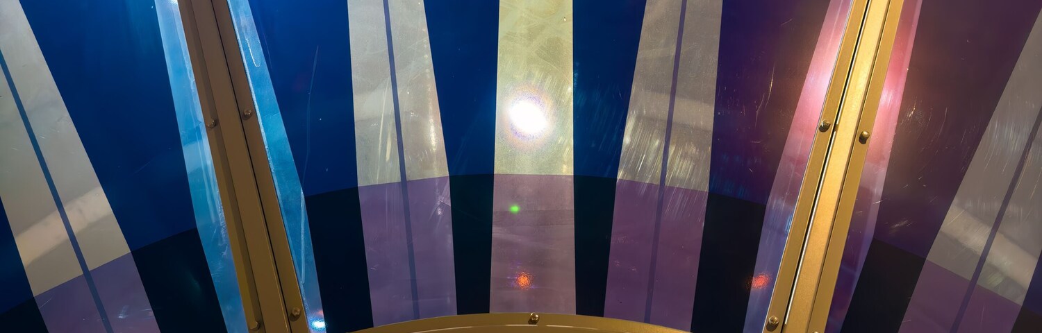 A circular, multi-colored ceiling with vertical stripes and a central yellow light fixture.