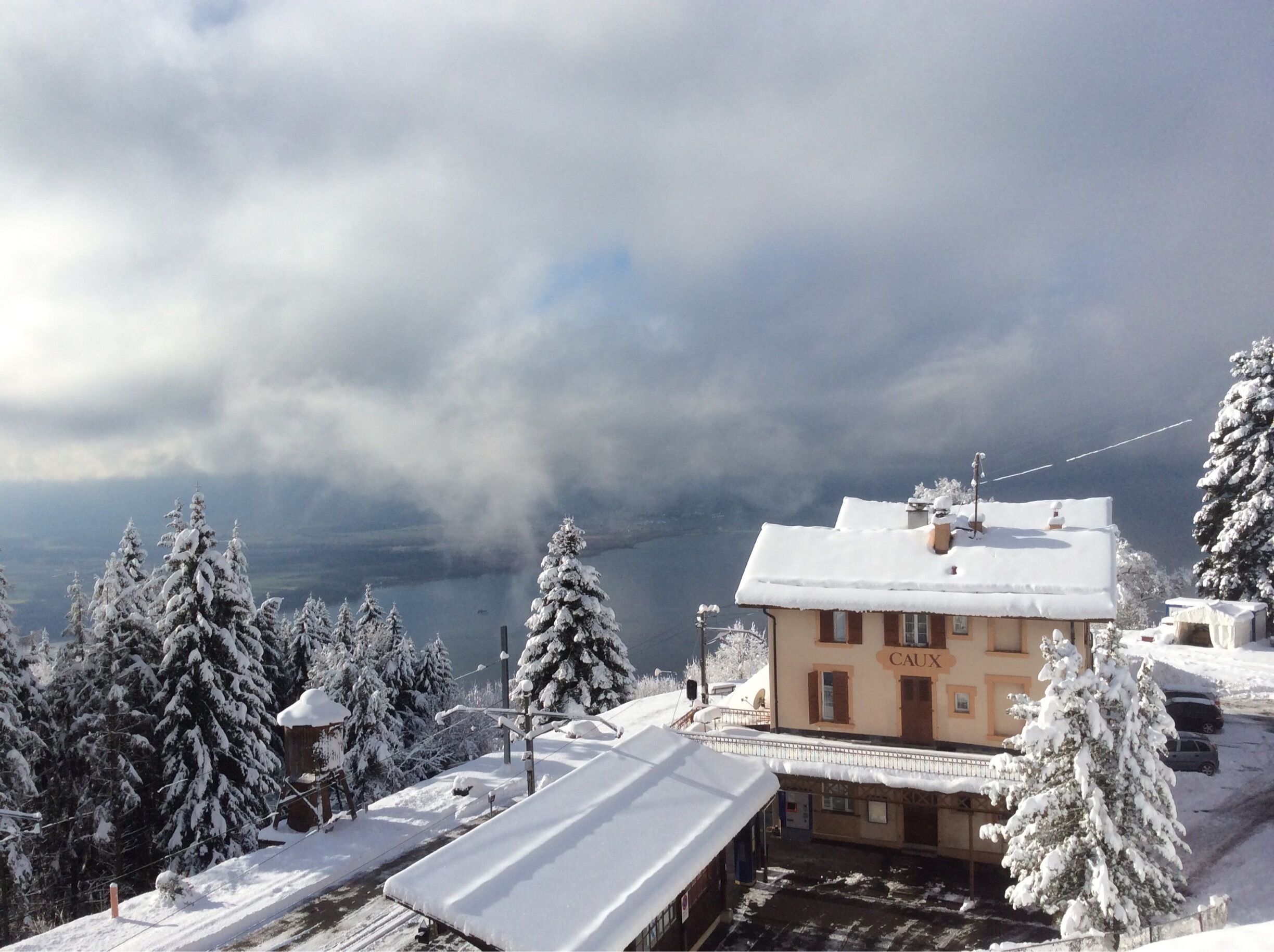 A snow-covered building with the sign "CAUX" in a mountainous area.